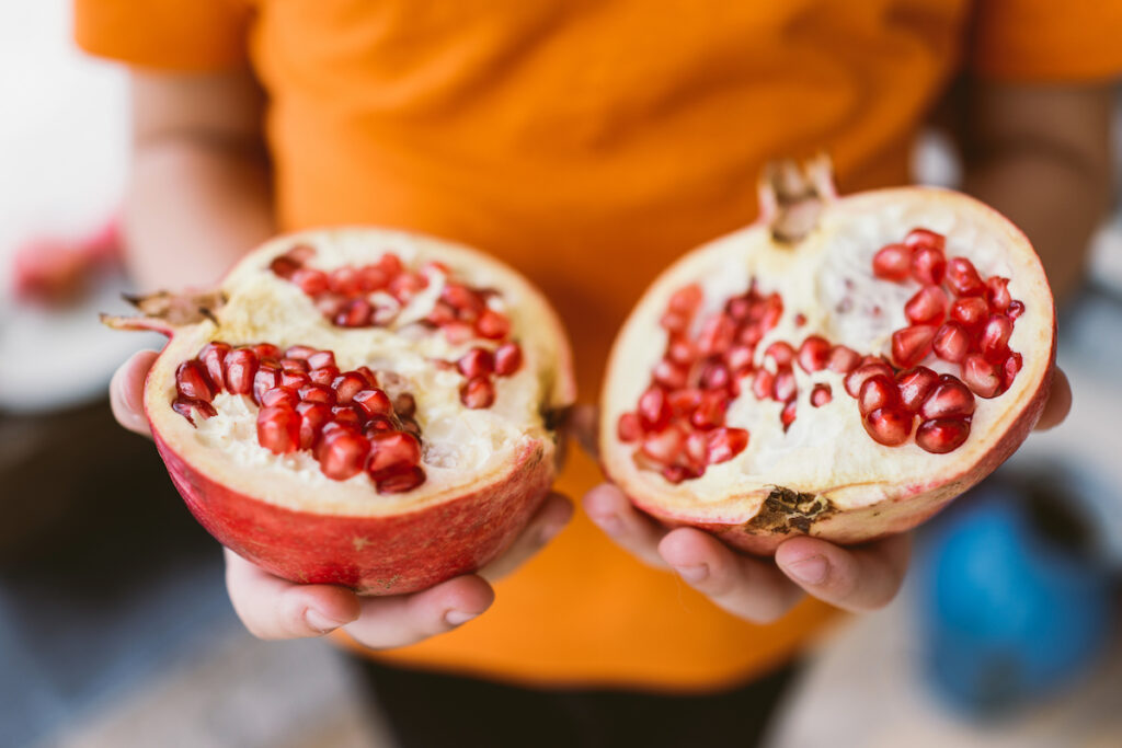 A woman holds a fresh pomegranate that's been halved