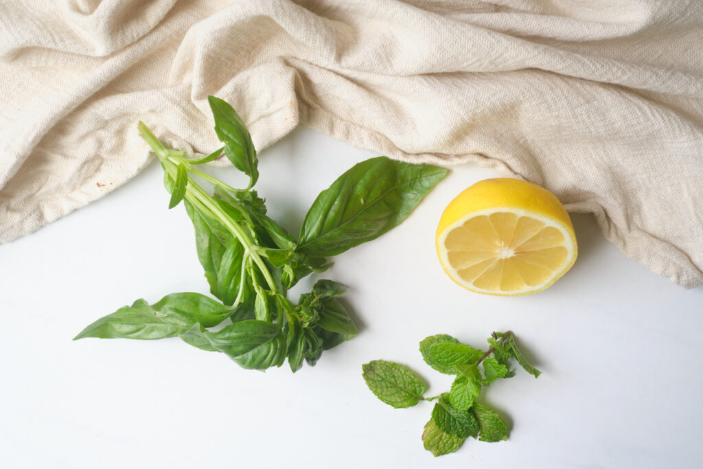 fresh mint, basil and lemon on a white table with a muslin cloth