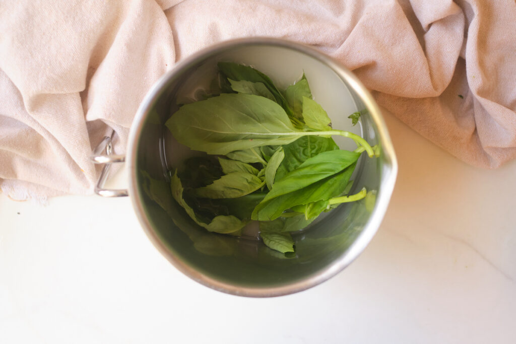 basil leaves in a pot of sugar water showing how to make basil simple syrup