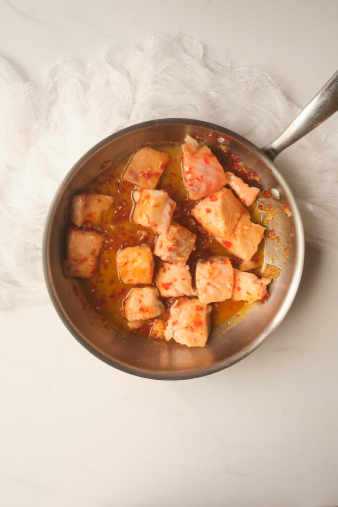 Cooked sweet chili salmon cubes in a skillet