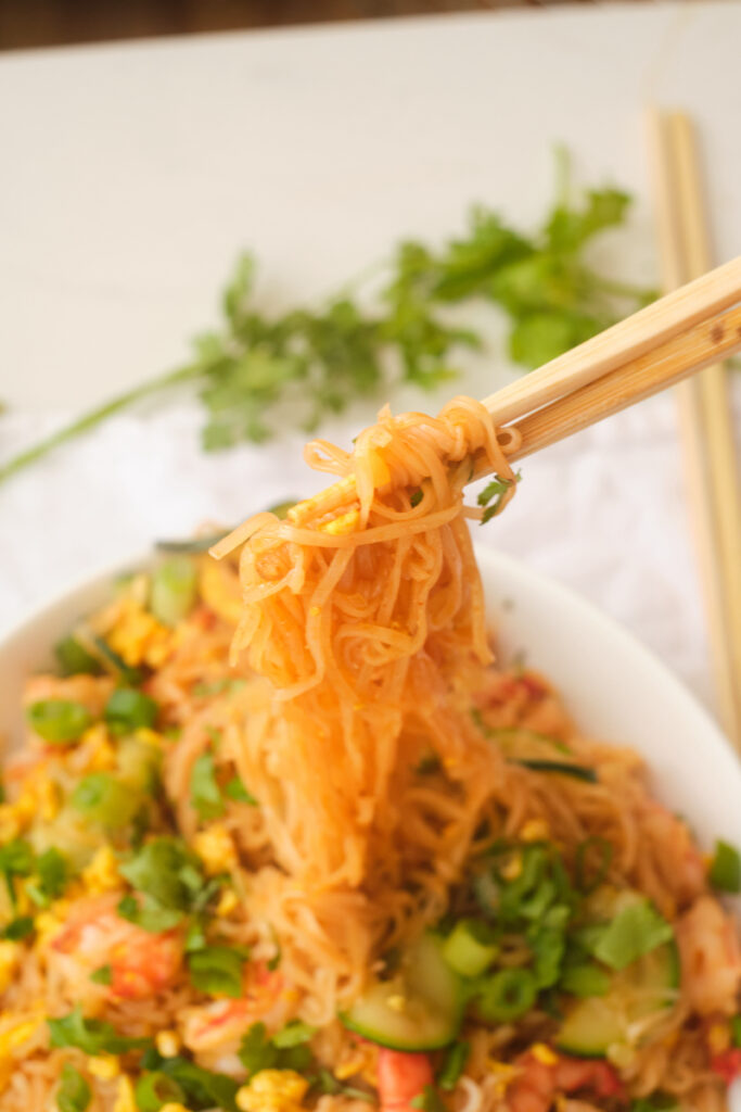 Chopsticks lift rice noodles from a bowl