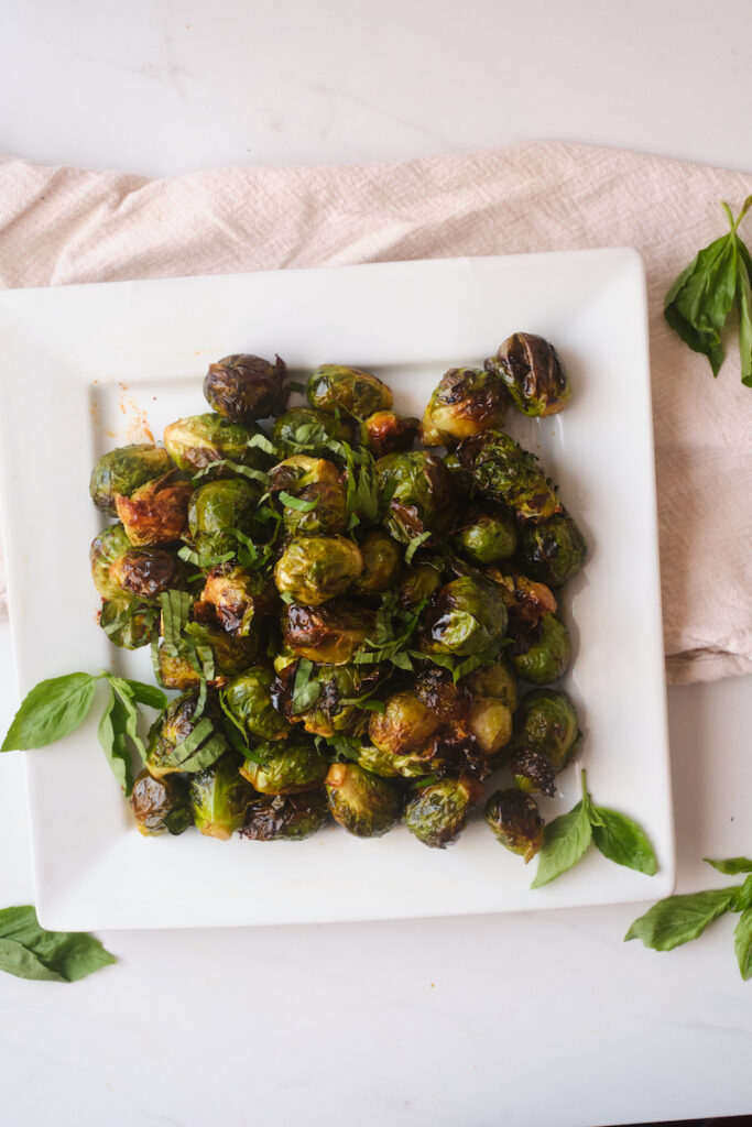 Sweet and spicy brussel sprouts with basil on a white plate for serving