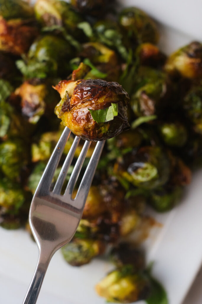 A charred roasted brussel sprout on a fork with basil chiffonade seen