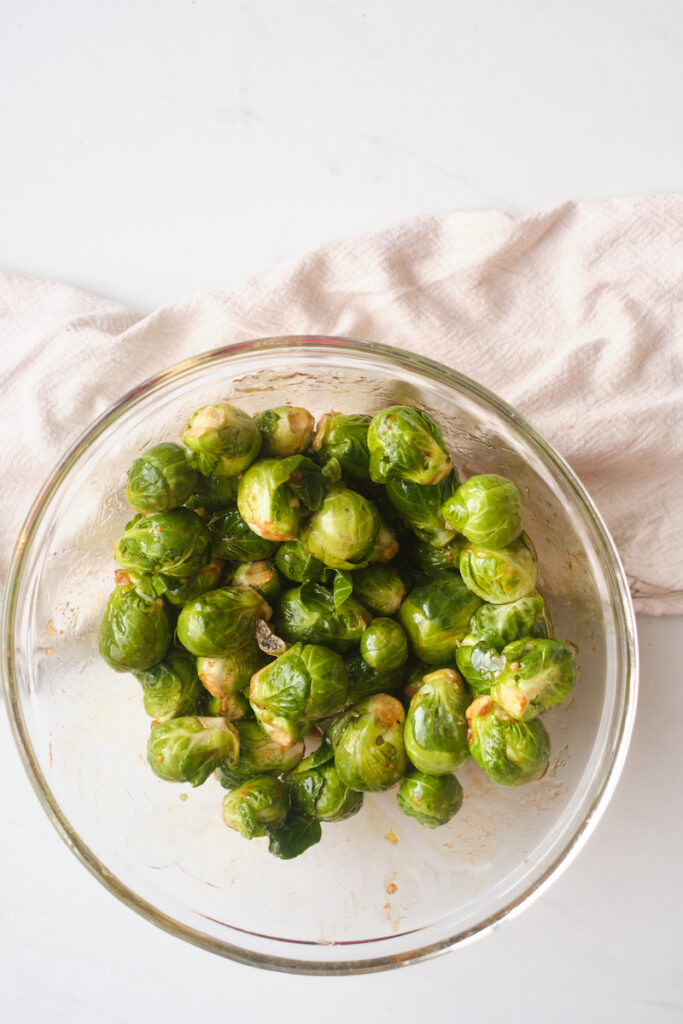 brussel sprouts in a bowl tossed with ingredients to make sweet and spicy brussel sprouts with basil
