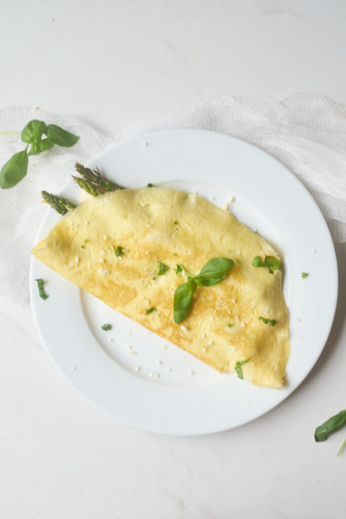 Asparagus omelette with goat cheese and basil on a plate. What goes well with basil? Asparagus does!