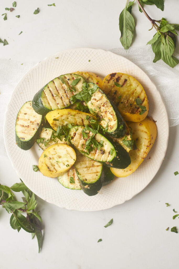 grilled zucchini and summer squash with thai basil in a serving dish