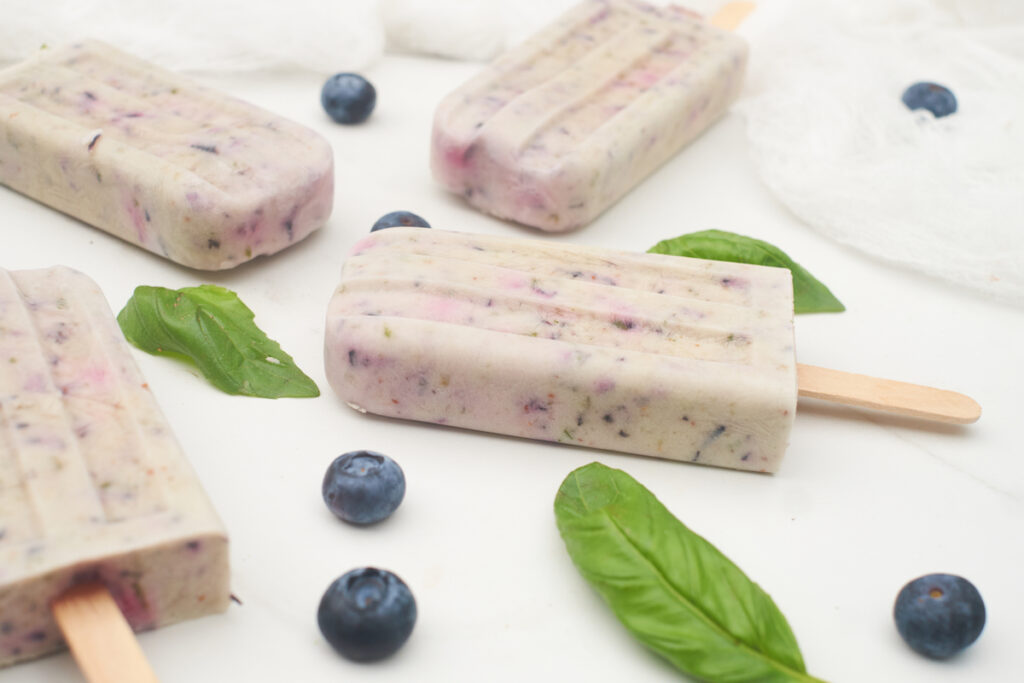 homemade coconut milk popsicles flavored with blueberry, pomegranate and basil