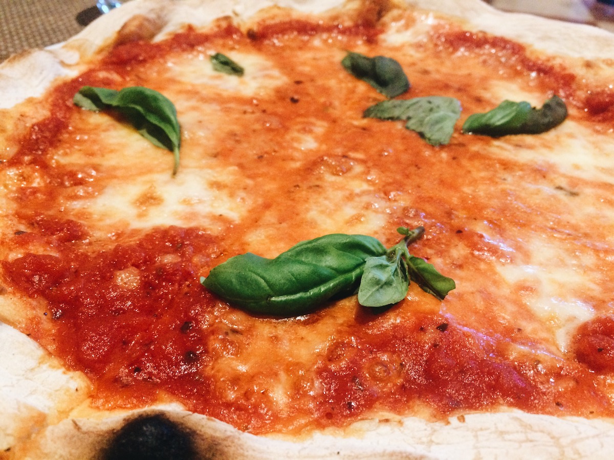 Close up of a margarita pizza with fresh basil leaves