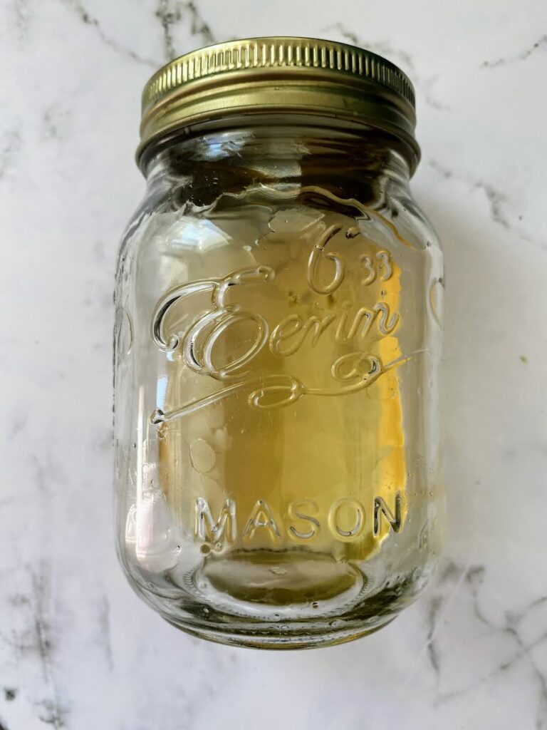homemade lemon basil syrup in a mason jar on a white marble counter